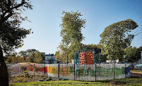a playground is painted in rainbow colors behind a fence