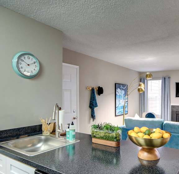 A kitchen with a black countertop and a blue couch.