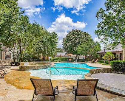 the pool is surrounded by chairs and trees