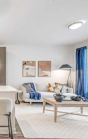 A living room with a brown couch, a coffee table, and a painting on the wall.