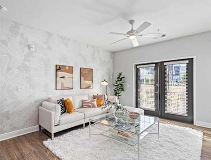 A living room with a white couch and a glass coffee table.