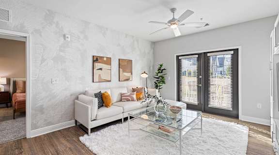 A living room with a white couch and a glass coffee table.