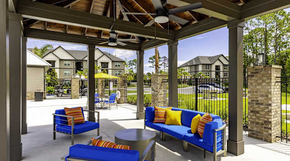 A patio with blue couches and a ceiling fan.