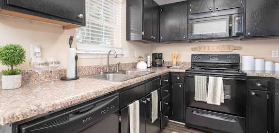 A black kitchen with granite countertops and a black oven.