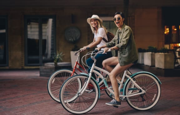 two women riding bikes on the street