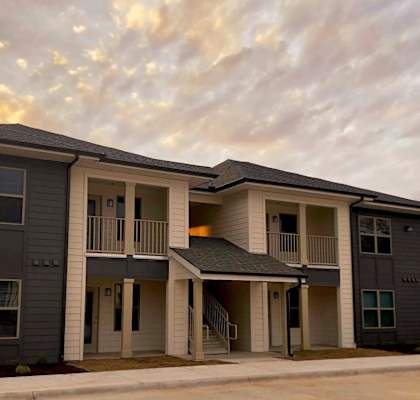 A row of modern townhouses with a cloudy sky in the background.