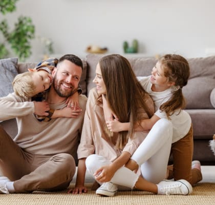 Family of Four Sitting in Living Room Together Smiling