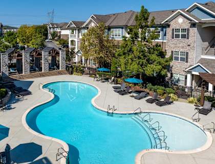 A large swimming pool surrounded by lounge chairs and umbrellas.