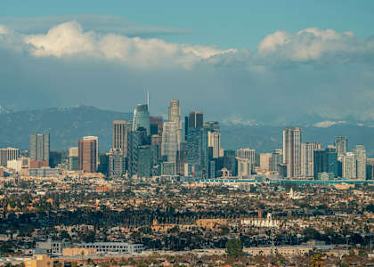 A city skyline with tall buildings and a mountain range in the background.