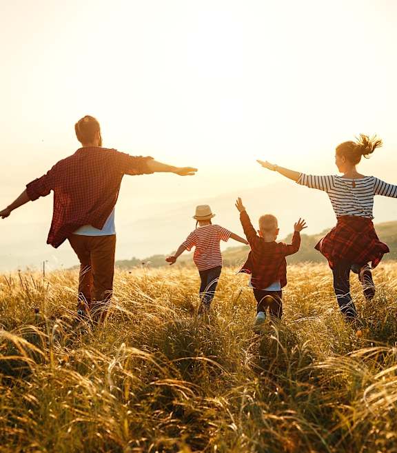 Family Running Through Field at Sunset