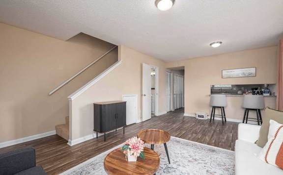 A living room with a staircase and a flat screen TV.