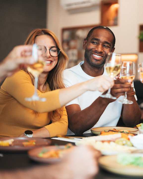 Three people toasting with champagne glasses at a dinner table.
