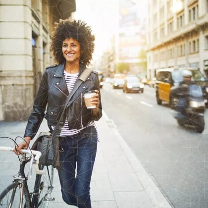 confident young woman walking down the street with her bike