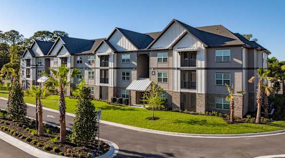 A large, modern apartment complex with a well-maintained lawn and landscaping.