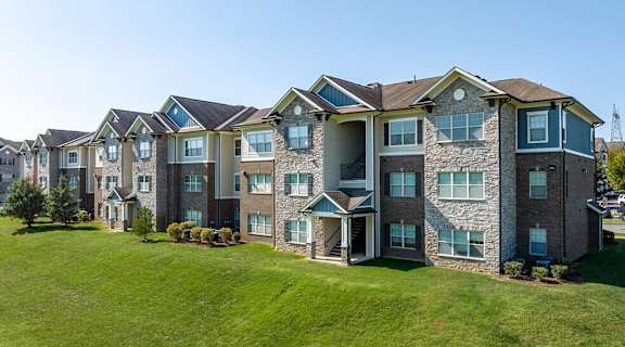 an exterior view of an apartment building on a green lawn