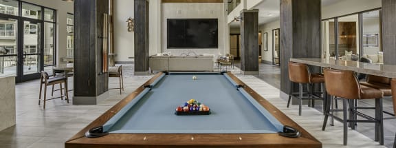 a pool table sits in the middle of a room with a bar and a television in the