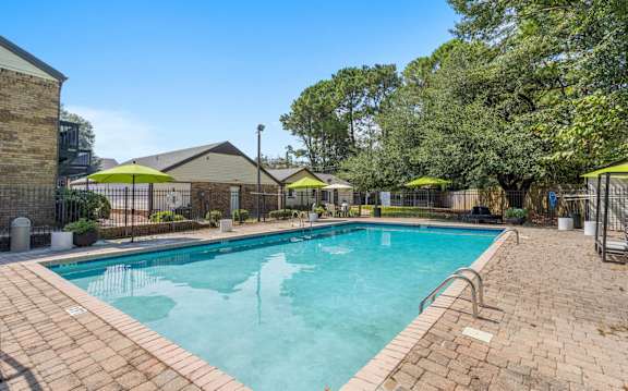 A large outdoor swimming pool surrounded by a brick patio.