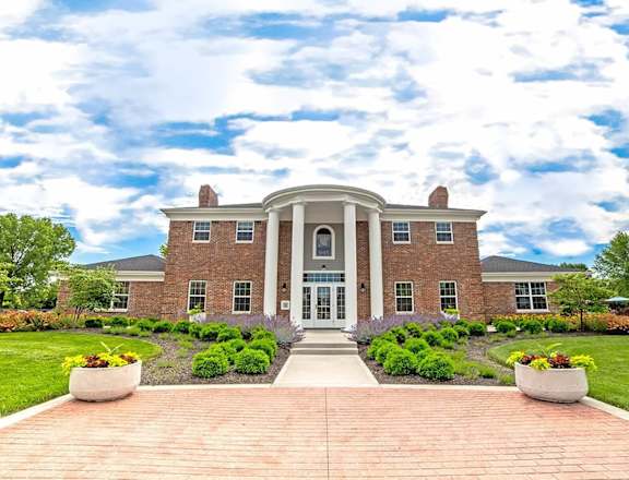 A large brick house with a front porch and a driveway at Gramercy Apartments, Carmel