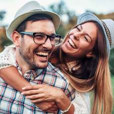 A man and a woman are laughing together in a park.