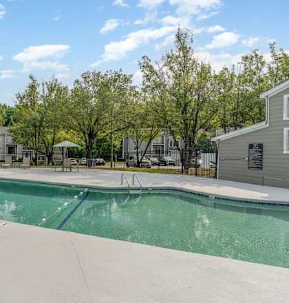 a swimming pool with trees and buildings in the background  at Village 1373, Greensboro, North Carolina