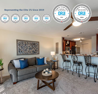 A living room with a grey couch, a coffee table, and a bar area with stools.
