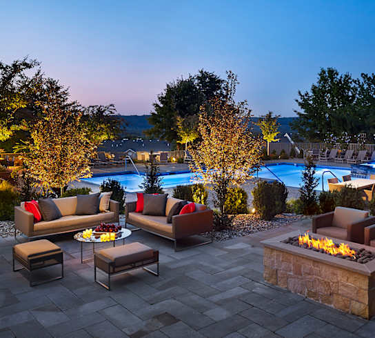 a backyard patio with couches and a fire pit at night at AVE Malvern, Malvern
