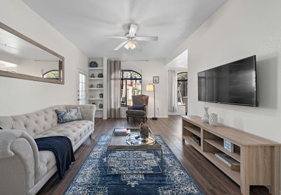 A living room with a blue rug and a white sofa.