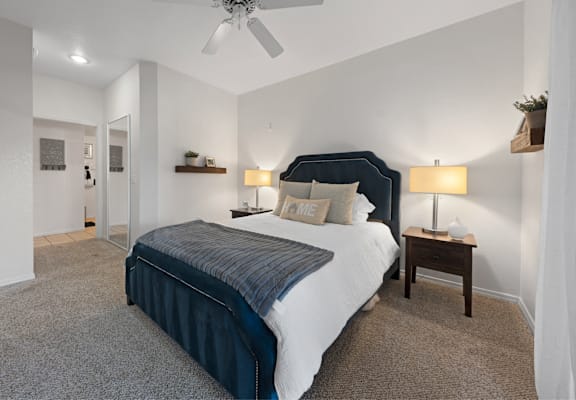 A bedroom with a bed, nightstand, and ceiling fan.
