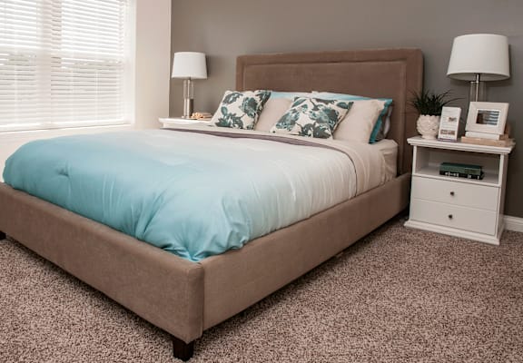 A bed with a blue cover and a brown headboard is in the image.