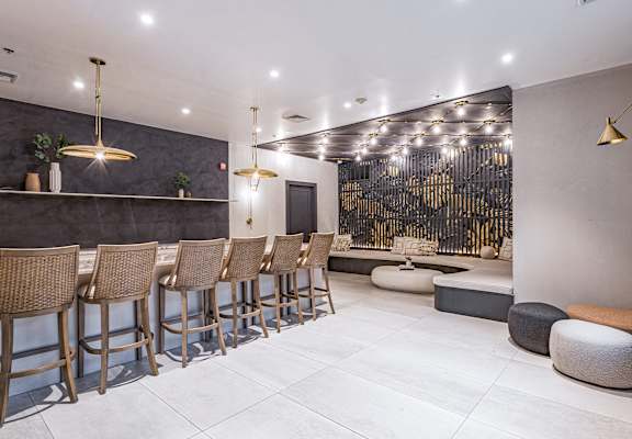 a bar with high chairs and stools in front of a wall with a gold design