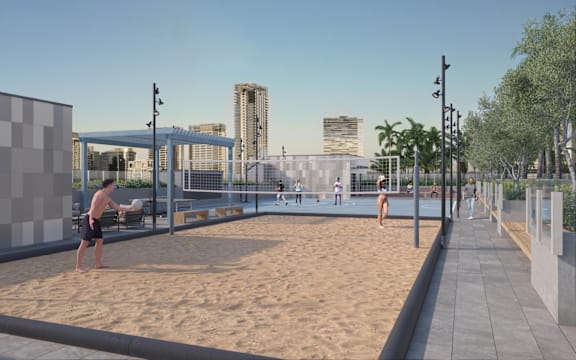 A man is playing beach volleyball in a sandy area with a city skyline in the background.
