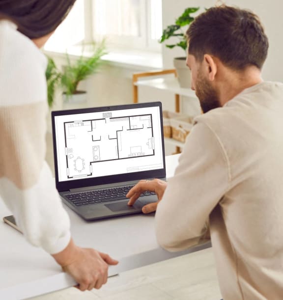 Man and Woman Looking at Floor Plans on Laptop