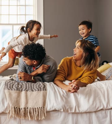 a family of four playing on a bed at Gateway Village, Colorado, 80701