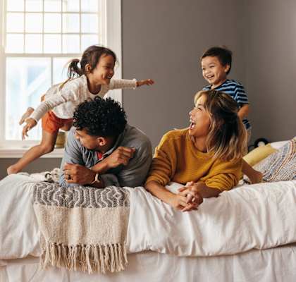 a family of four playing on a bed at Gateway Village, Colorado, 80701