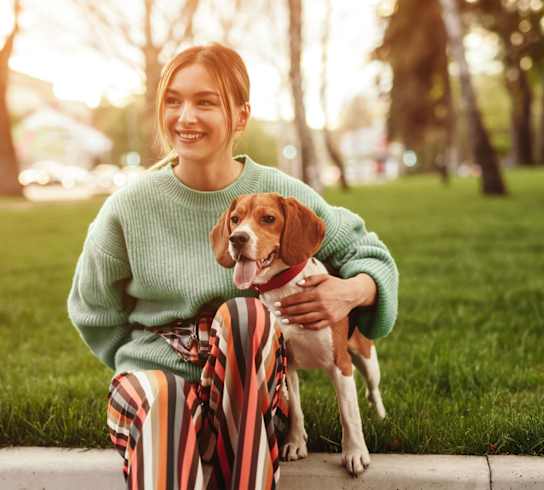 a woman in a green sweater sitting on a curb with her dog at Market Club at The Mill Apartments, Sacramento ,95818