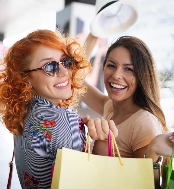 three women holding shopping bags and smiling at the camera