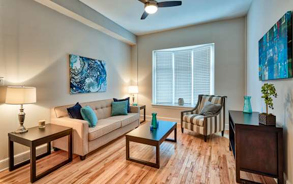 A living room with a couch, two chairs, a coffee table, and a painting on the wall.