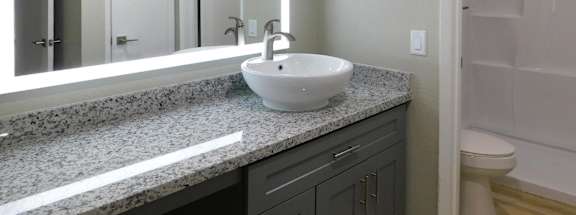 A bathroom with a granite countertop and a white sink.