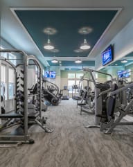 a large fitness room with cardio equipment and flat screen tvs