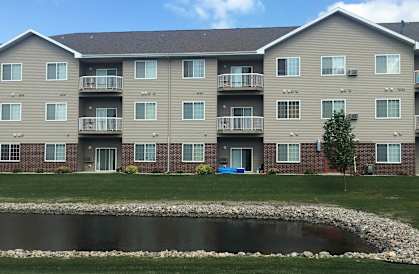 an apartment building with a small pond in front of it