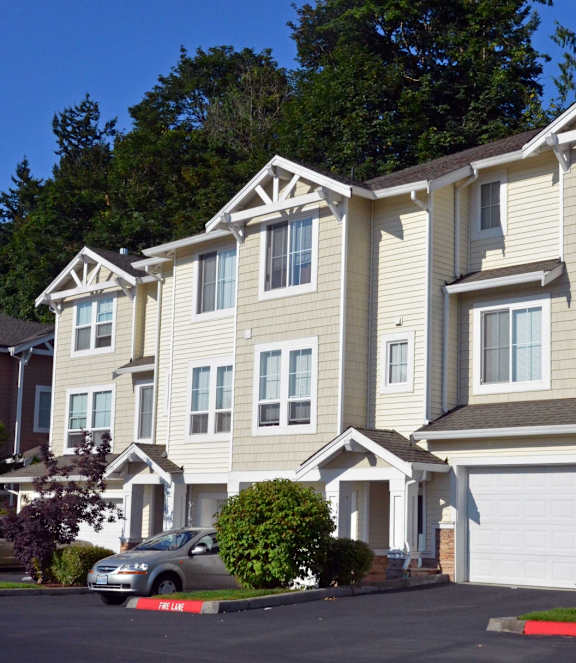 A large, multi-story residential building with a car parked in front.