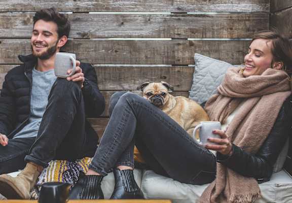 Man, woman, and dog sitting on a couch