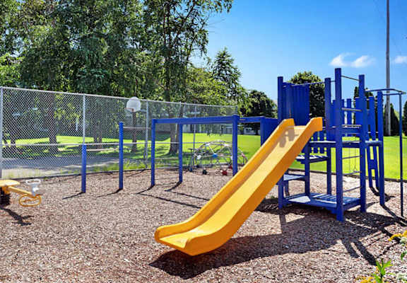 A playground with a yellow slide and a blue structure.