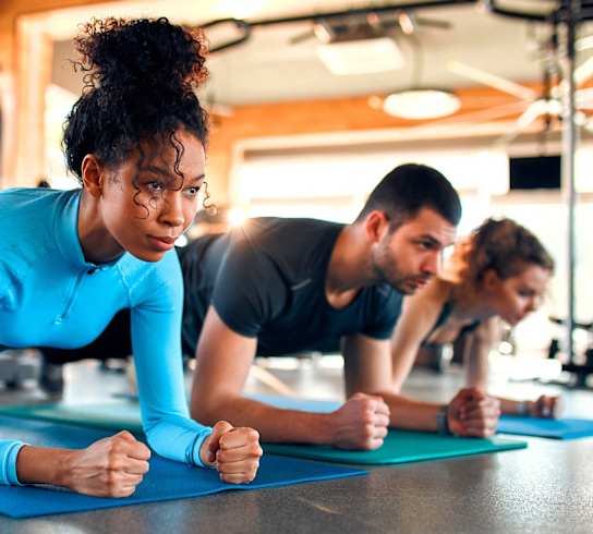 a group of people doing pushups on mats in a gym