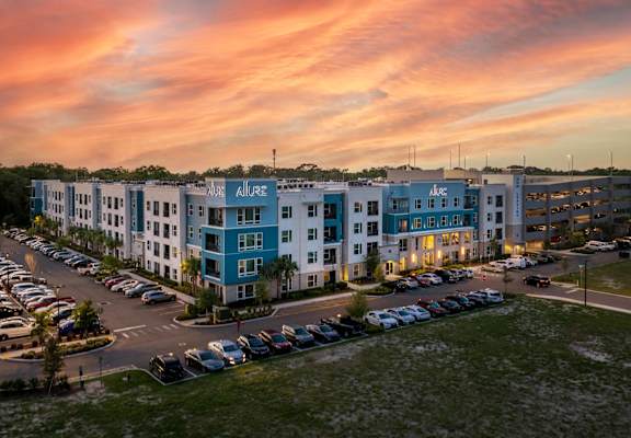 A large apartment complex with a parking lot in front.