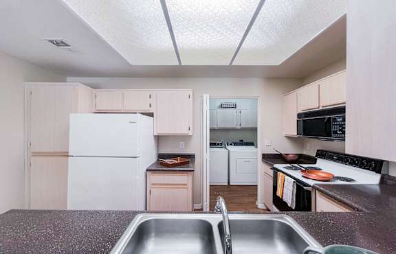 A kitchen with a white fridge and a stainless steel sink.