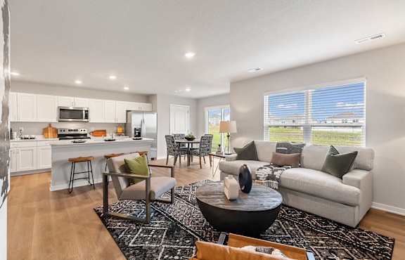 A modern living room with a kitchen in the background.