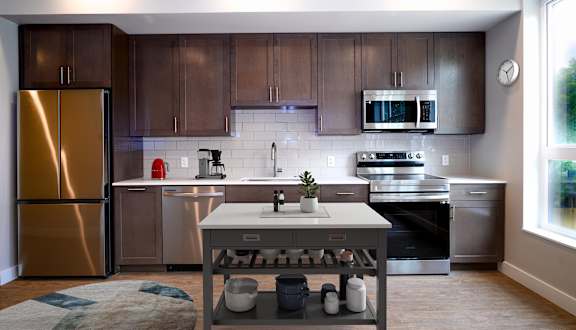 A modern kitchen with a refrigerator, microwave, oven, and sink.