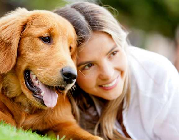 A woman and a dog are lying on the grass.