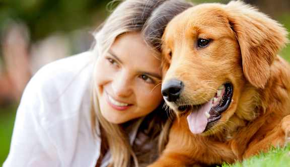 A woman and a dog are lying on the grass.